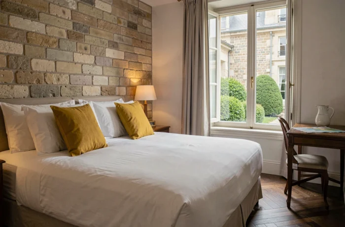 Chambre d'hôtel confortable à Dijon avec mur en pierre apparente, parquet en chêne et vue sur une cour intérieure paisible